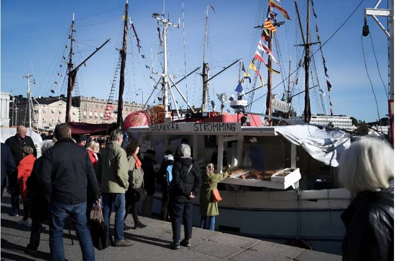 People crowd around the fishing boats in Helsinki harbour to buy fresh herring