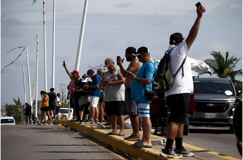 Люди отчаянно пытаются найти сигнал, чтобы воспользоваться своими мобильными телефонами после того, как ураган Отис обрушился на Акапулько, Мексика.