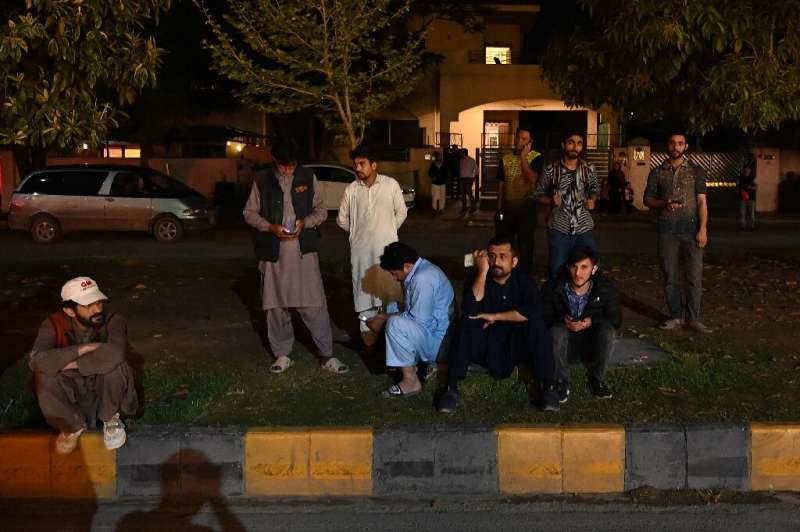 People gather by the side of the road after fleeing a high-rise building in Islamabad following the earthquake