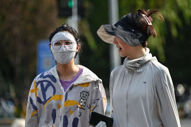 People in Beijing wear protective clothing as the Chinese capital bakes under a record-breaking run of high temperatures