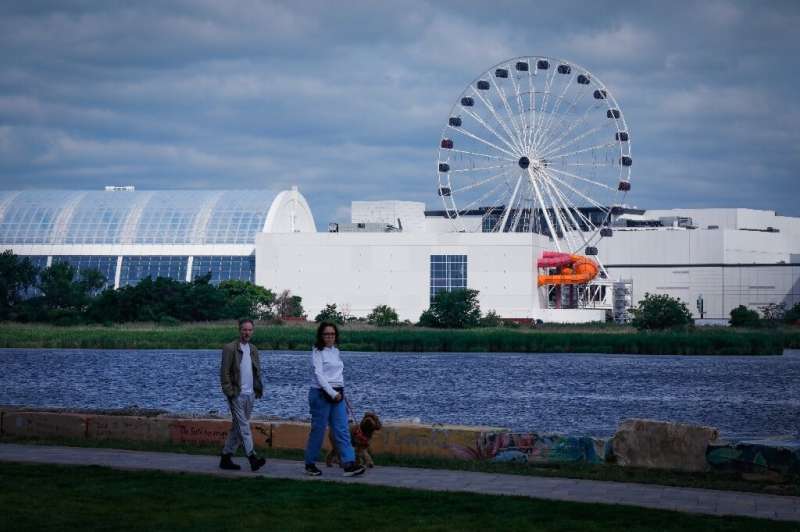 People stroll along the Hackensack River in New Jersey with the American Dream Mall in the background