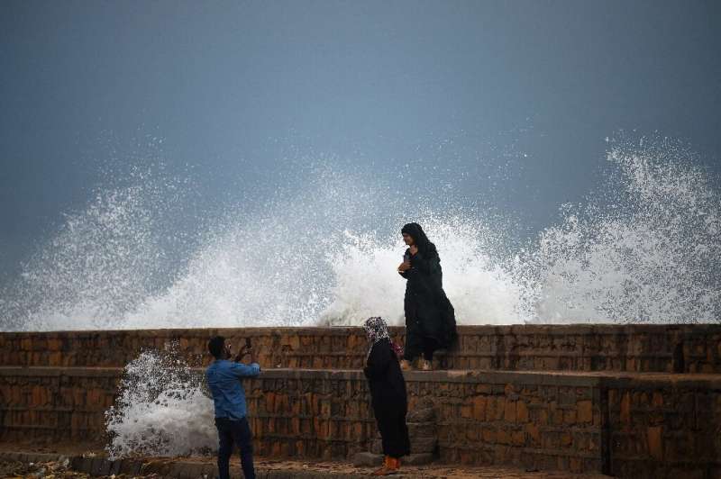 People take photos by a waterfront in Karachi as Cyclone Biparjoy approaches on Wednesday