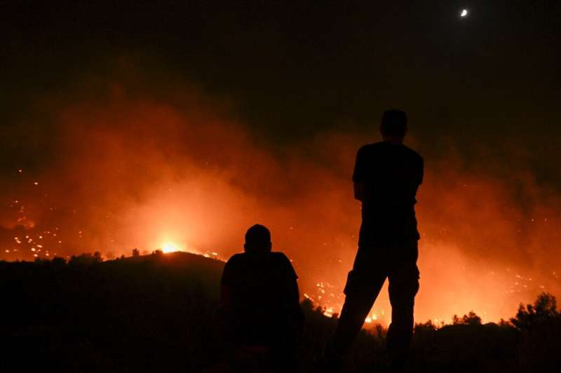 People watch the fires on Greece's Rhodes, where tens of thousands of people evacuated