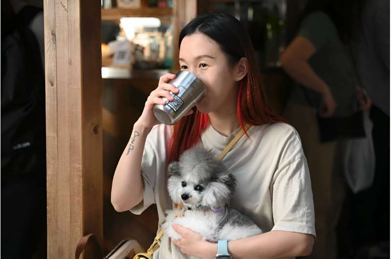Pet groomer Lucine Mo drinks coffee out of a thermal mug with a QR code at a coffee shop in Hong Kong