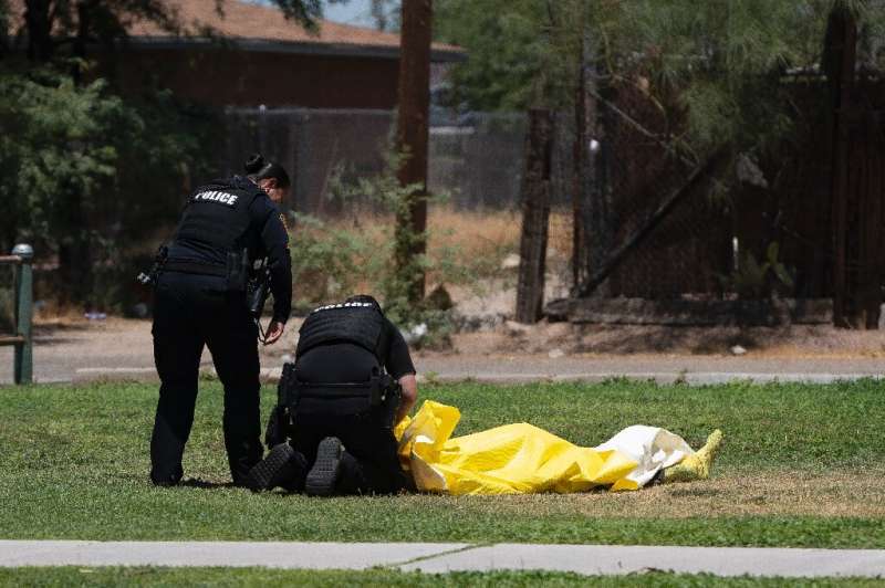 Police officers tend to a dead homeless person whose body temperature was 102 degrees Fahrenheit (about 39 Celsius) at the time 