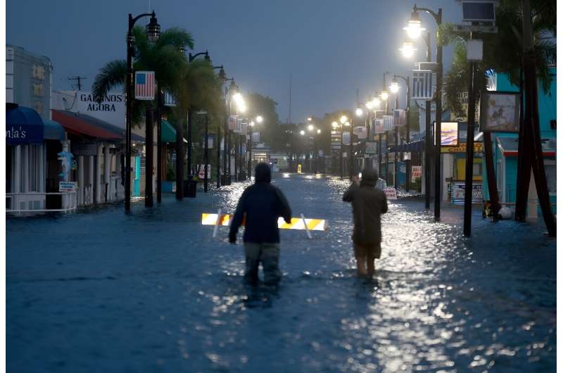 Reporters wade through flood waters in downtown Tarpon Springs after Hurricane Idalia passed offshore on August 30, 2023
