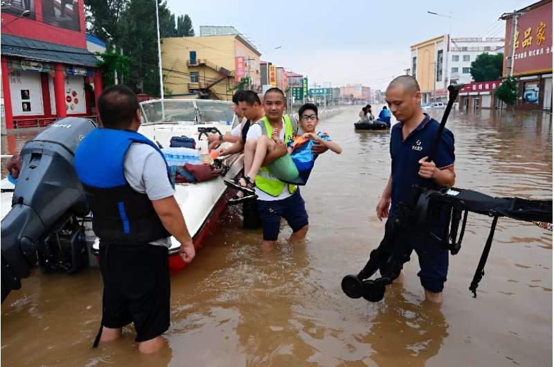 Rescuers evacuate residents from a flooded area following heavy rains in Zhuozhou, in northern China's Hebei province on August 