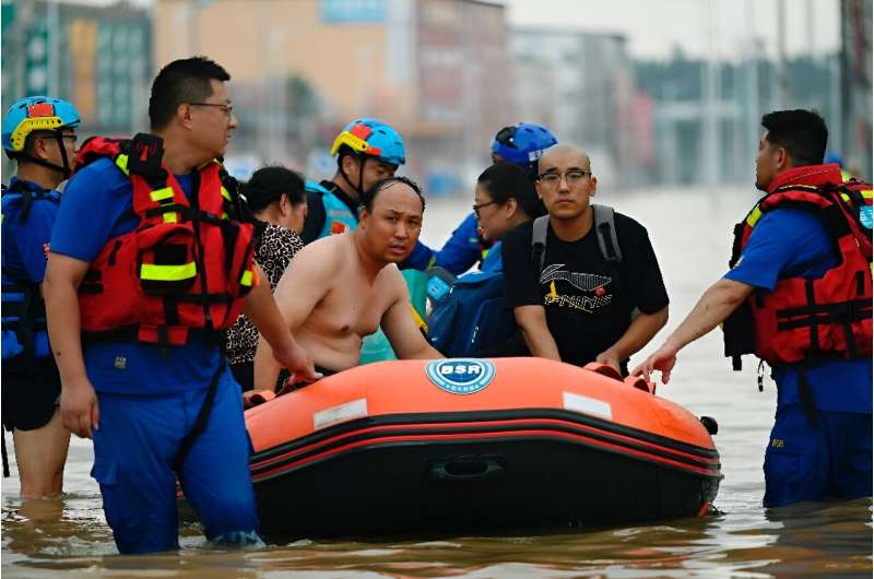 Rescuers wade in a flooded road as they evacuate residents following heavy rains in Zhuozhou, in northern China's Hebei province