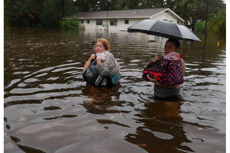 Residents wade through flood waters after having to leave their home on August 30, 2023 in Tarpon Springs, Florida
