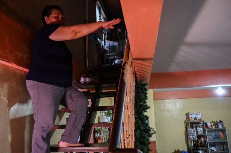 Rowena Jimenez shows the height of the floods inside her home