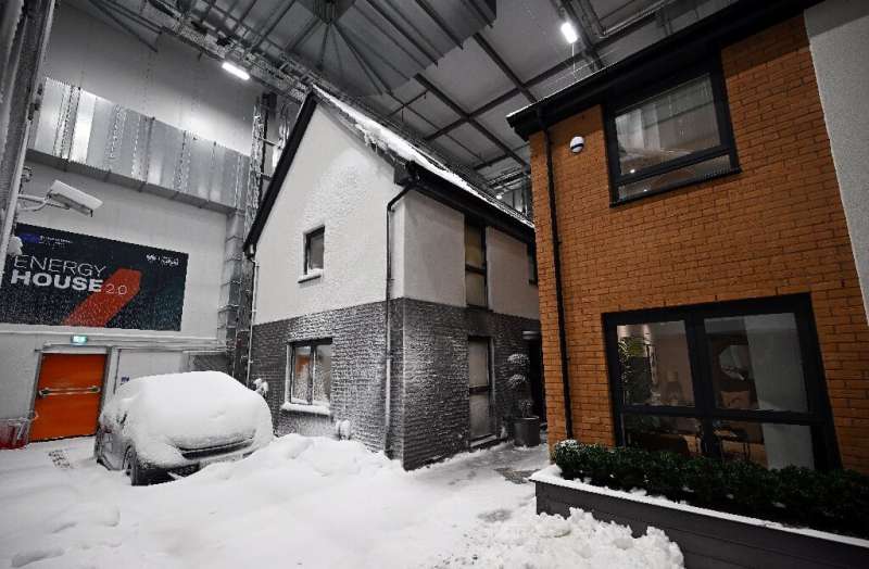 Simulated snow covers a car and the walls of one of two houses built in a lab to develop future heating solutions that will use 