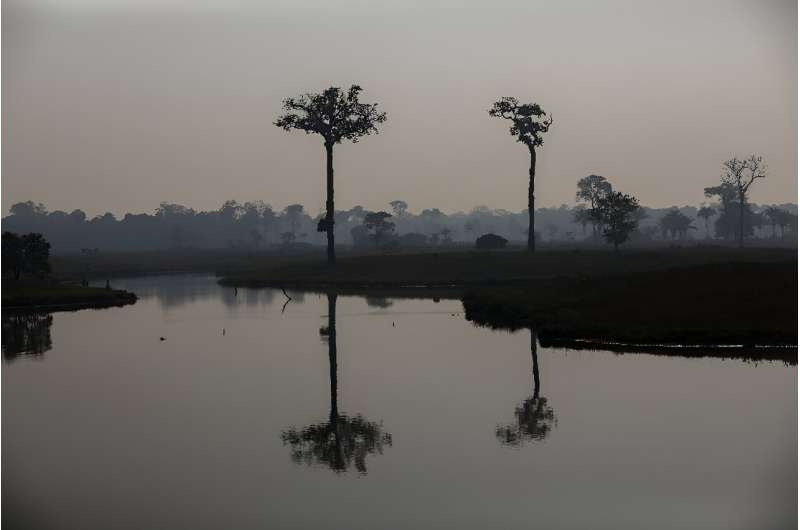 Smoke from illegal fires lit by farmers rises over a river in Careiro, Amazonas state, in September 2023