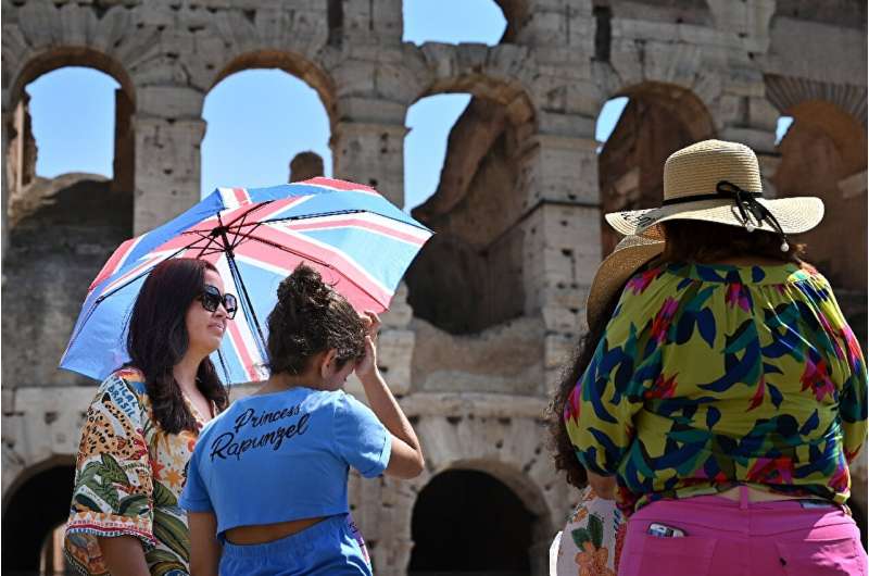 Tourists sheltered from the sun with umbrellas at the Colosseum in Rome