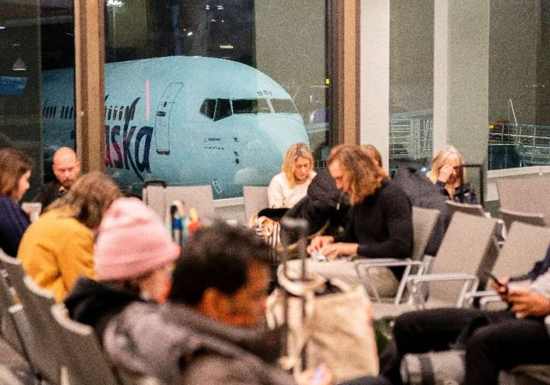 Travelers wait as an Alaska Airlines plane sits at a gate at Los Angeles International Airport on January 11, 2023