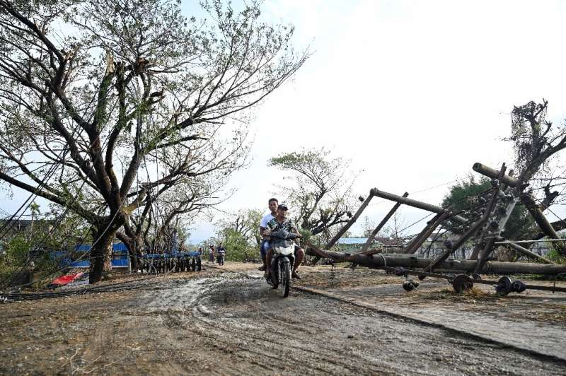 Two men drive past fallen utility poles in Kyauktaw in Myanmar's Rakhine state, hit by Cyclone Mocha