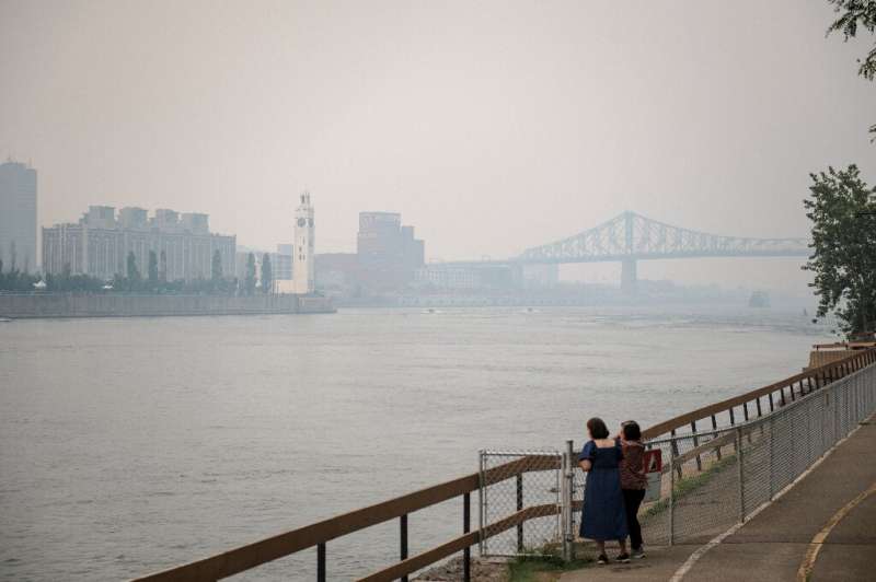 Two women look at Montreal's Jacques-Cartier Bridge through the smoke caused by wildfires in Northern Quebec on June 25, 2023