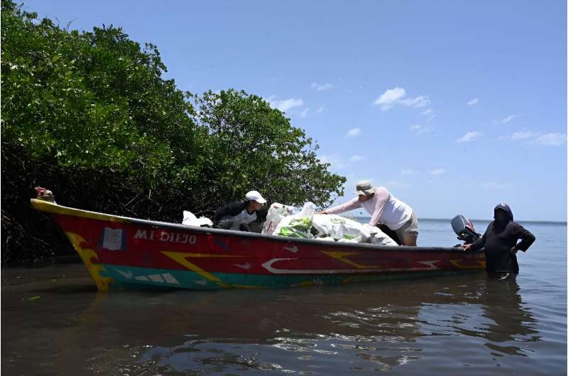 Voluntarios cargan un bote con desechos encontrados en una isla de anidación de aves marinas en el Golfo de Fonseca