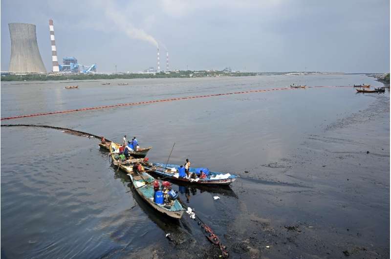 Workers collect oil after it a spill in the aftermath of Cyclone Michaung on the outskirts of Chennai, India