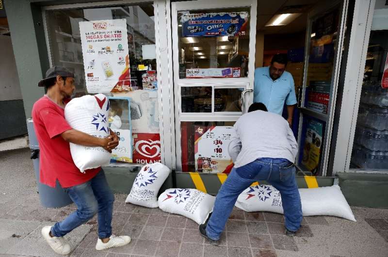 Workers place sandbags outside a shop in Mexico's Puerto Vallarta to protect against possible flooding