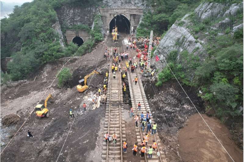 Workers repair a railway line in the aftermath of the flooding at a village following heavy rains