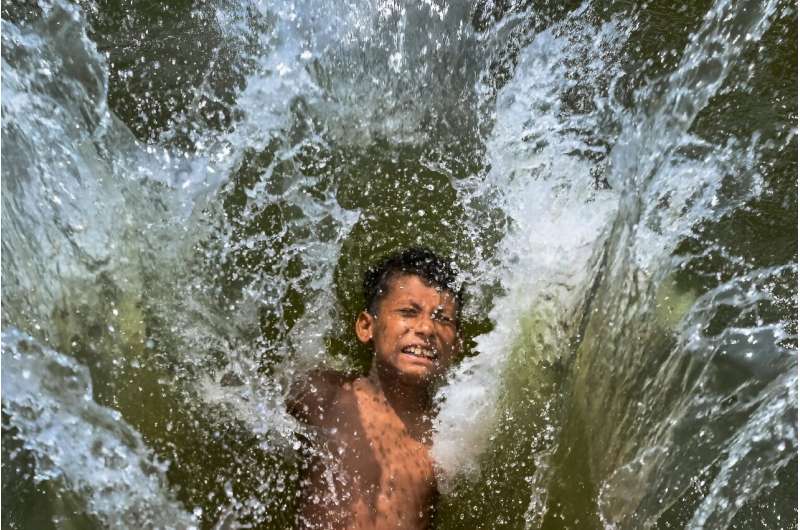 A child playfully takes a dip in a lake to get respite from the heat in Dhaka, Bangladesh