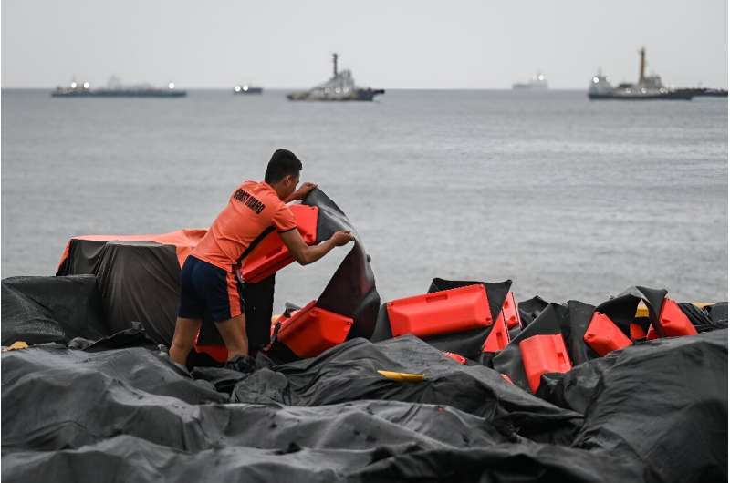 A coast guard staffer arranges an oil spill containment boom to be used in Manila Bay