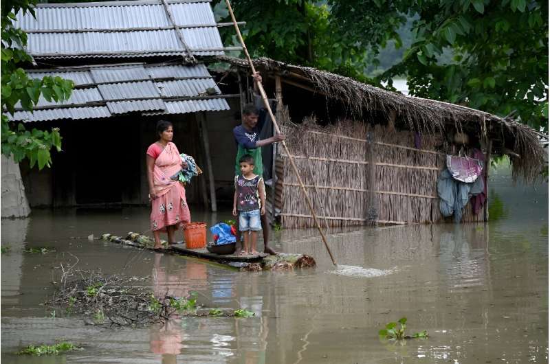 A family carries their belongings on a raft in India's flood-hit Assam state