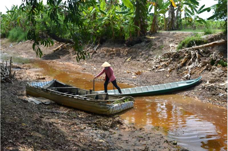 A farmer crosses an almost completely dried-up canal in southern Vietnam's Ca Mau province, which suffered a prolonged heatwave in February