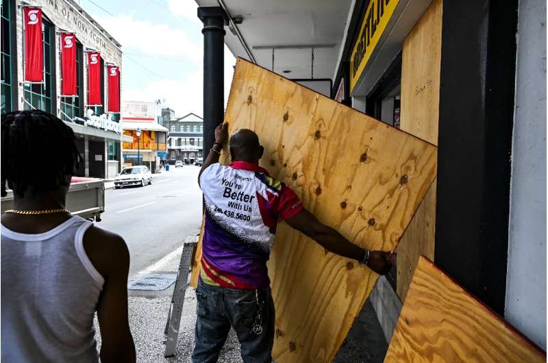 A man boards up a shop window as people prepare for the arrival of Hurricane Beryl in Bridgetown, Barbados