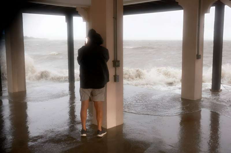 A man checks on his neighborhood as high winds, rain and storm surge from Hurricane Debby inundate  Cedar Key, Florida