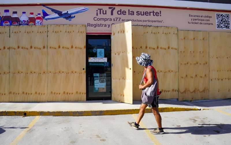 A man walks past a boarded-up store in Tulum, Quintana Roo State, Mexico