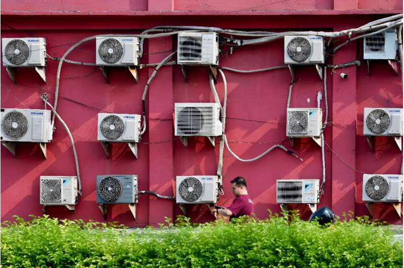 A man walks past air conditioning units installed on a shop wall in Jakarta