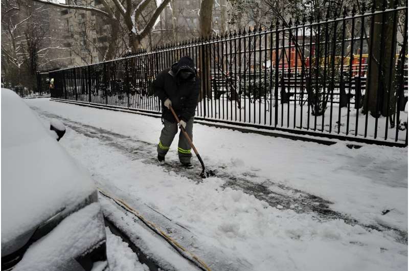 A municipal worker clears sidewalks of snow in Manhattan