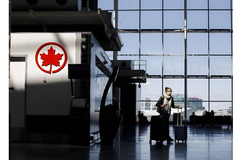 A passenger wheels her luggage near an Air Canada logo at Toronto Pearson International Airport in April 2020