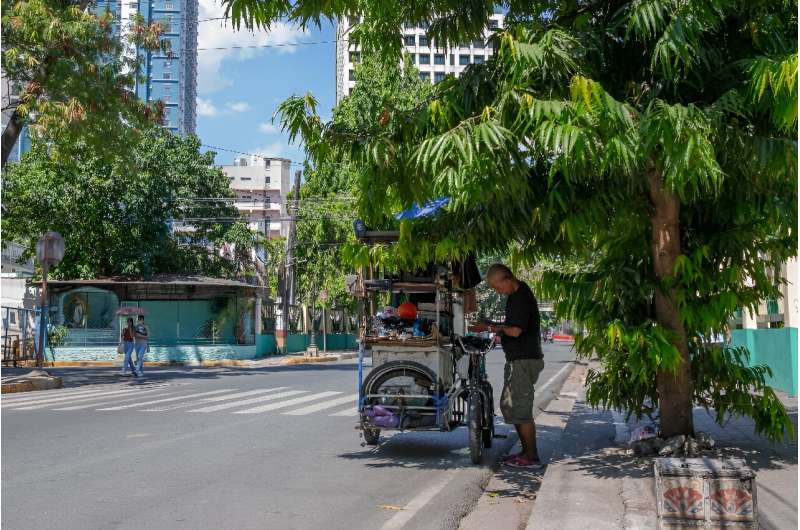 A vendor stands under a tree during hot weather in Manila. The Philippines has suspended in-person classes in all public schools for two days because of the extreme heat