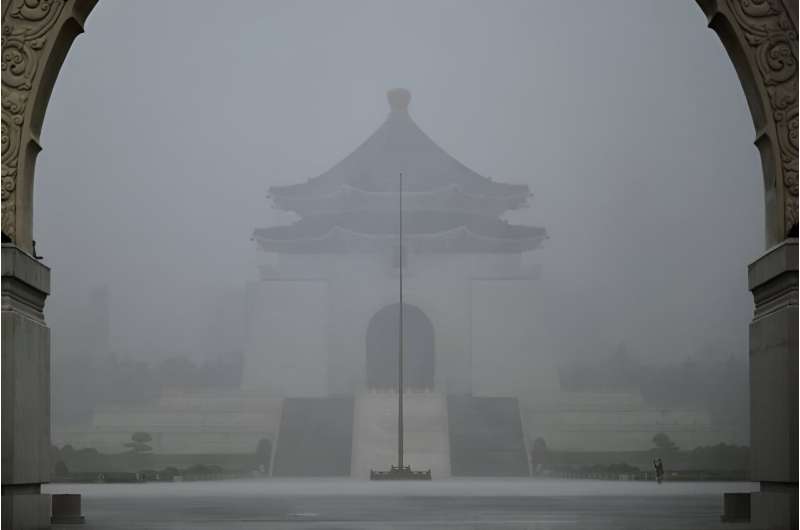 A visitor takes photographs in front of the Chiang Kai-shek Memorial Hall in heavy rain caused by Typhoon Gaemi in Taipei