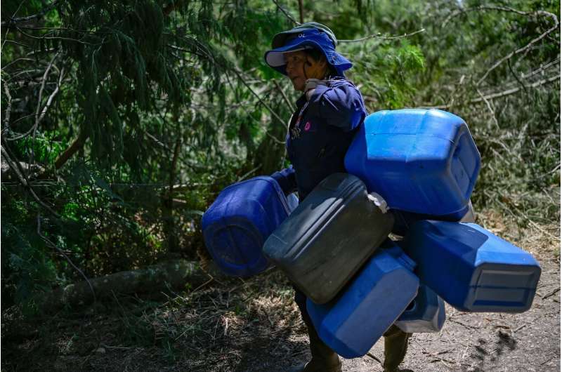 A woman carries water jugs to help to put out the forest fire in Nemocon, Colombia
