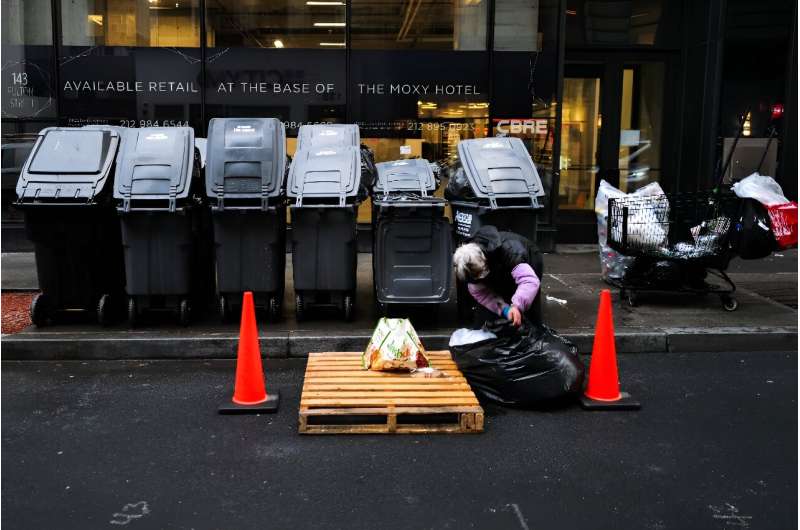A woman searches through a trash bag in Manhattan on March 20, 2024