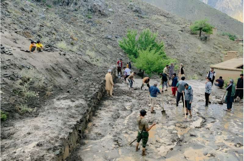 Afghan residents shovel mud following flash floods after heavy rainfall at Pesgaran village in Dara district, Panjshir province