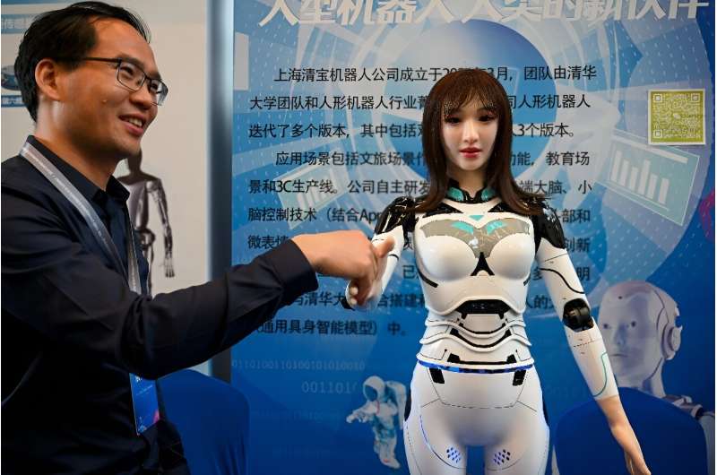 An exhibitor shakes hands with a humanoid robot at the 2024 China Humanoid Robot Developers Conference in Shanghai