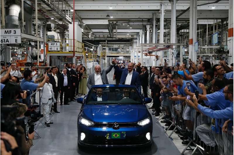 Brazilian President Luiz Inacio Lula da Silva (L) and his vice-president, Geraldo Alckmin, greet workers as they visit the Volkswagen car factory