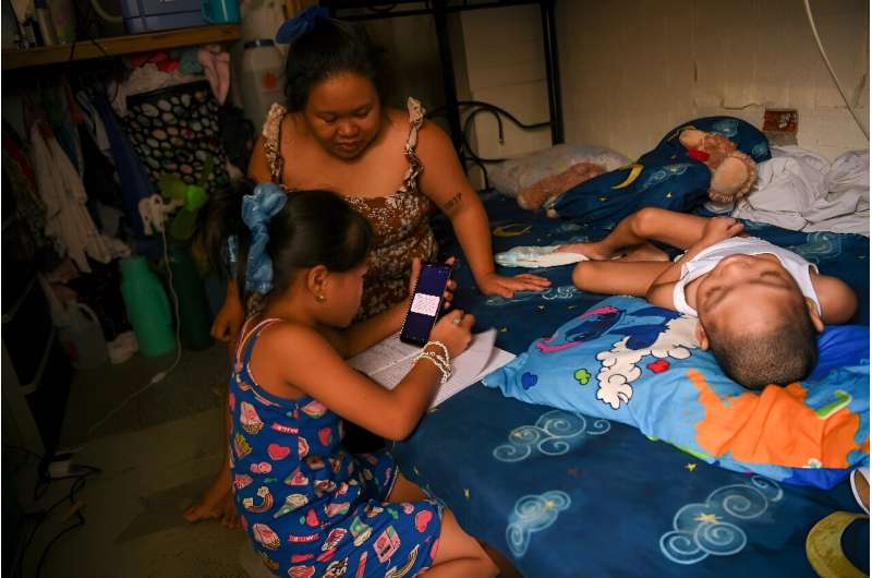 Cindella Manabat (C) helps her daughter Ella Araza (L) with homework, at their house in Manila