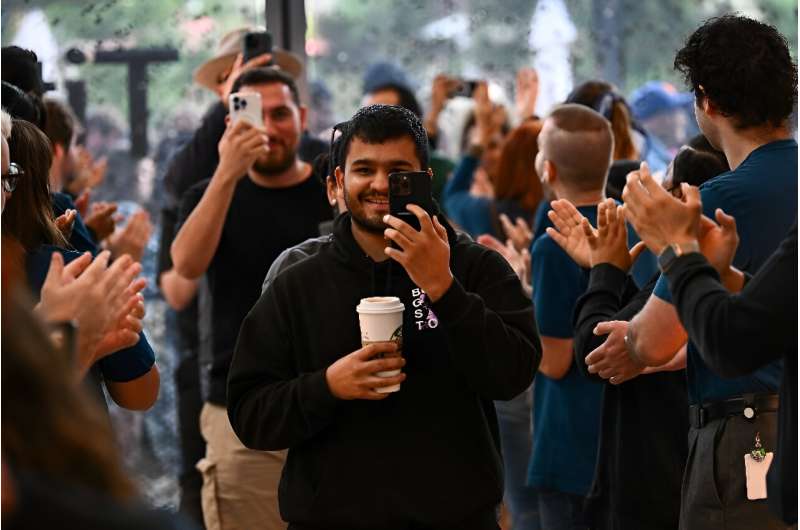 Employees applaud as the first customers enter the store to buy the Apple iPhone 15 series at The Grove Apple store in Los Angeles, California, on September 22, 2023