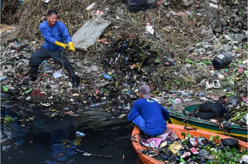 Government workers pick up trash under a bridge in Paranaque, Metro Manila
