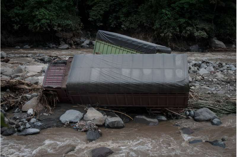 In the flood-hit district of Tanah Datar, the flooding left roads caked in mud, trucks sticking out of a nearby river and mosques smashed by logs and metal sheets