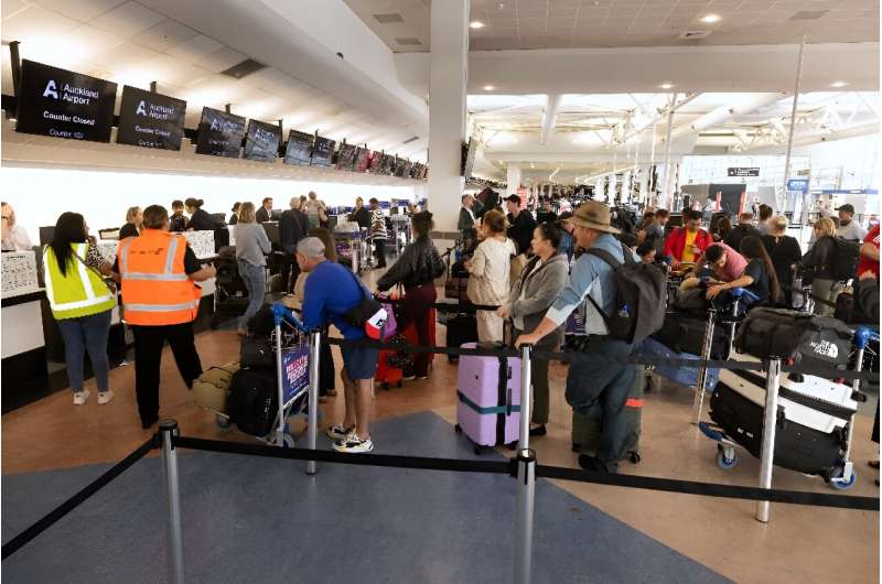 Passengers stand in a line at the LATAM Airlines check-in counters at Auckland International Airport in Auckland on March 12, a day after a Boeing-made LATAM plane bound for New Zealand suddenly lost altitude mid-flight