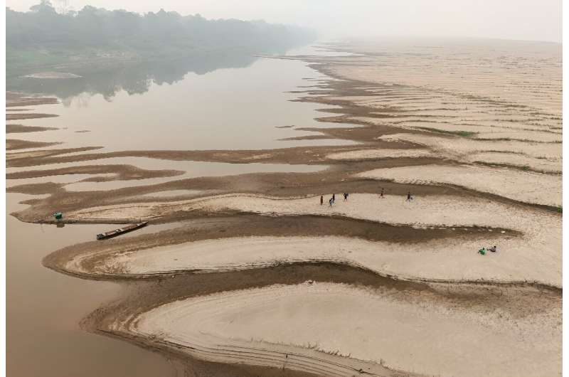 People carry drinking water along a sandbank of the Madeira River in the village of Paraizinho, Amazonas state, northern Brazil, September 7, 2024.