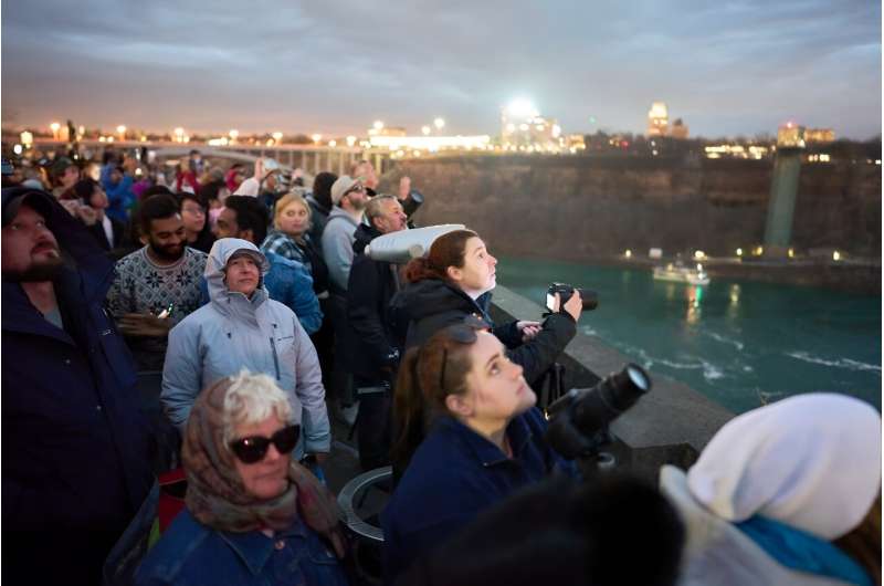 People look up at the sky as they prepare for the total eclipse which is set to pass over the region later in the day, in Niagara Falls, Canada