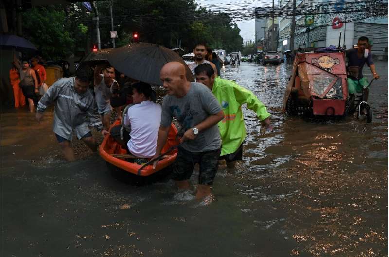 People making their way through a flooded street in Manila as Typhoon Gaemi hit