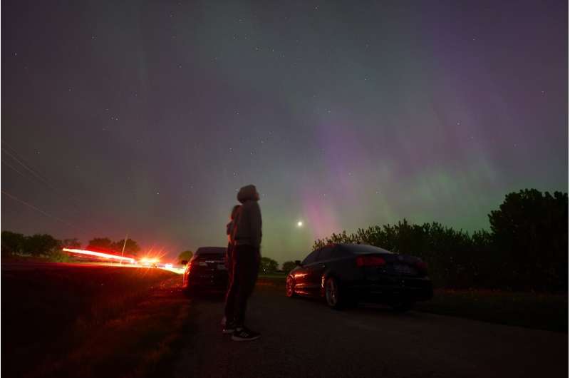 People stop along a country road near London, Ontario, to watch the Northern lights, or aurora borealis, during a geomagnetic storm